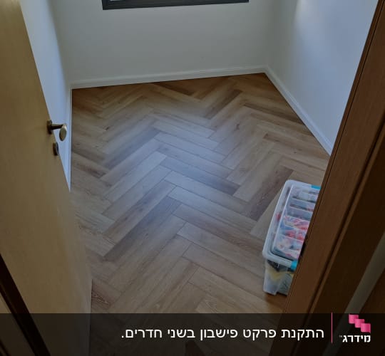רצפת פרקט עץ בהתקנה בחדר קטן עם חלון